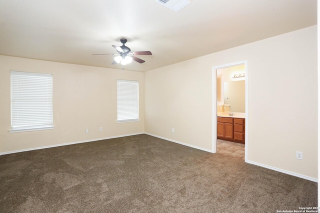 spare room with visible vents, dark carpet, baseboards, and ceiling fan