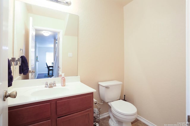 half bathroom with tile patterned flooring, baseboards, vanity, and toilet