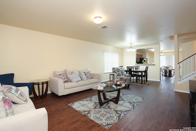 living room featuring wood finished floors, visible vents, baseboards, and stairs