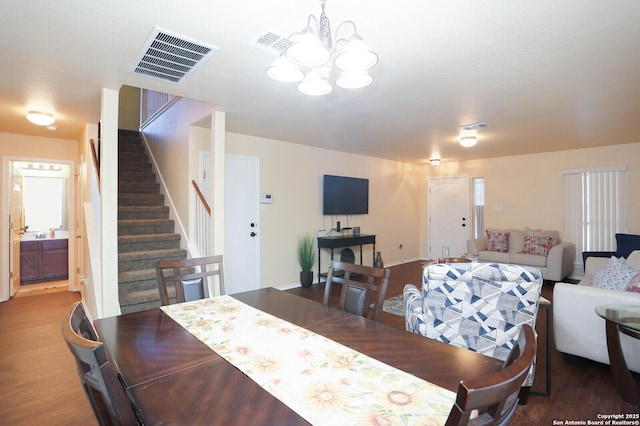 dining space with wood finished floors, visible vents, a notable chandelier, and stairs