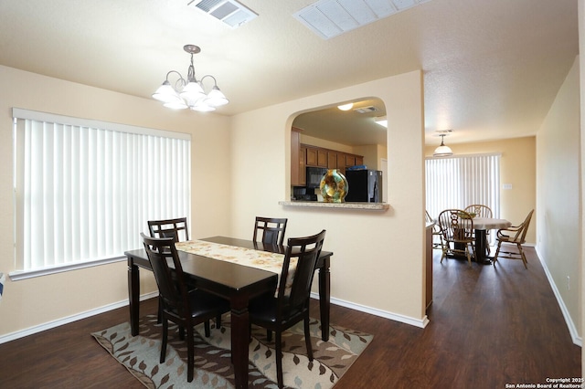 dining room featuring a healthy amount of sunlight, visible vents, dark wood finished floors, and baseboards