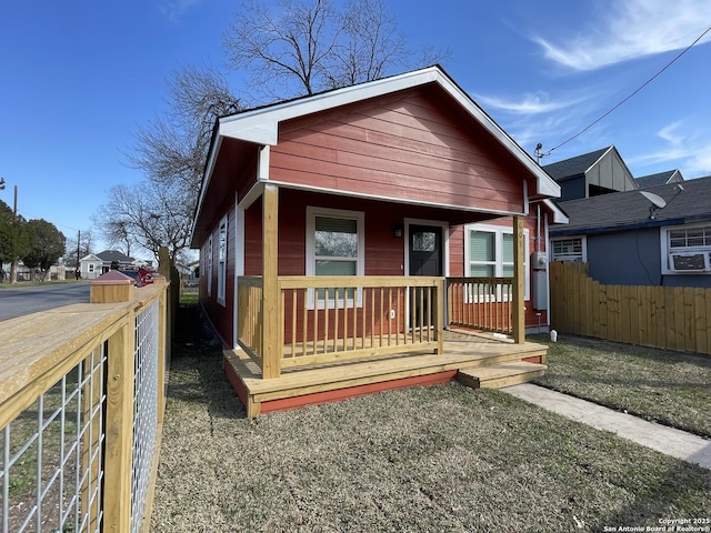 bungalow-style home with cooling unit, covered porch, and fence