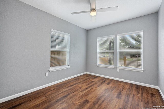 spare room featuring dark wood finished floors, baseboards, and a ceiling fan