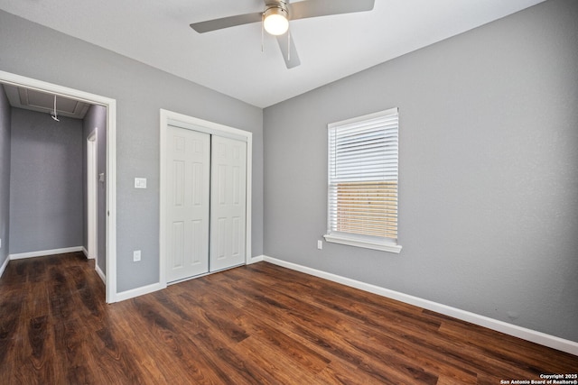 unfurnished bedroom with a closet, baseboards, attic access, and wood finished floors