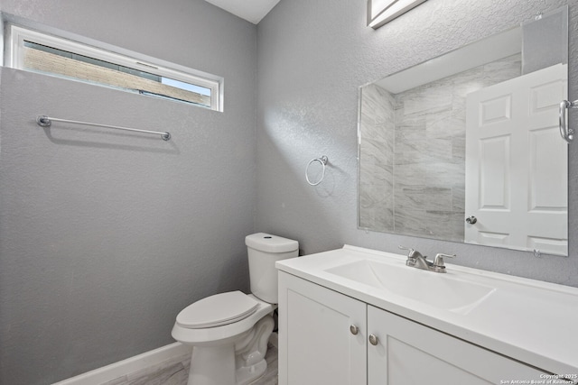 bathroom featuring toilet, vanity, and a textured wall