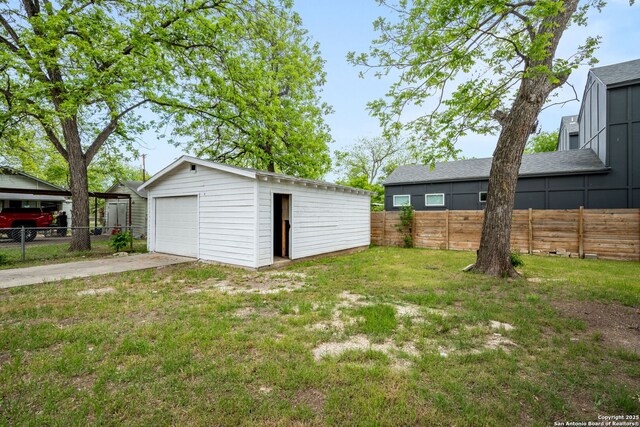view of yard with a garage, fence, driveway, and an outdoor structure