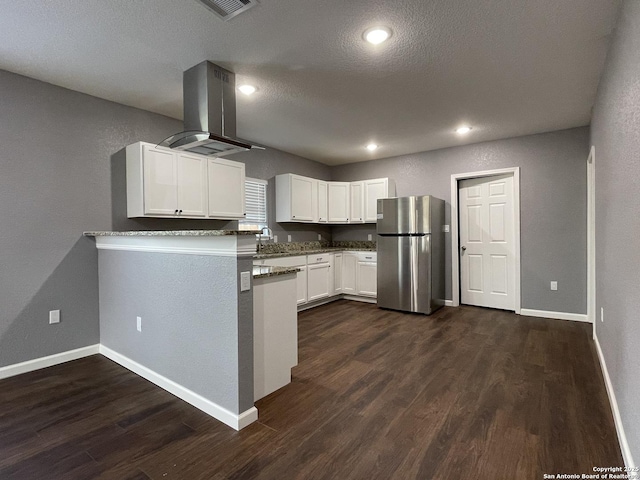 kitchen featuring dark wood-type flooring, freestanding refrigerator, white cabinets, island range hood, and baseboards