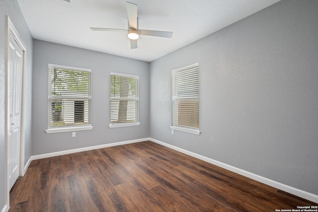 spare room featuring dark wood-style flooring, baseboards, and a ceiling fan
