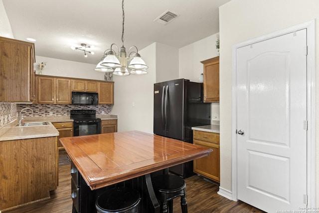 kitchen with brown cabinets, visible vents, backsplash, a sink, and black appliances