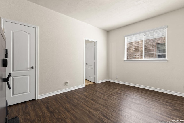 unfurnished bedroom featuring a textured wall, wood finished floors, and baseboards