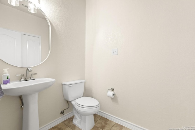 half bathroom with tile patterned flooring, baseboards, a sink, and toilet