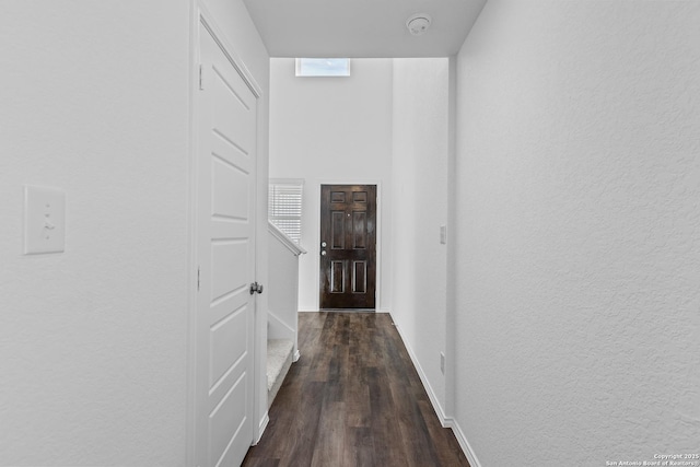 interior space featuring a textured wall, plenty of natural light, dark wood finished floors, and baseboards