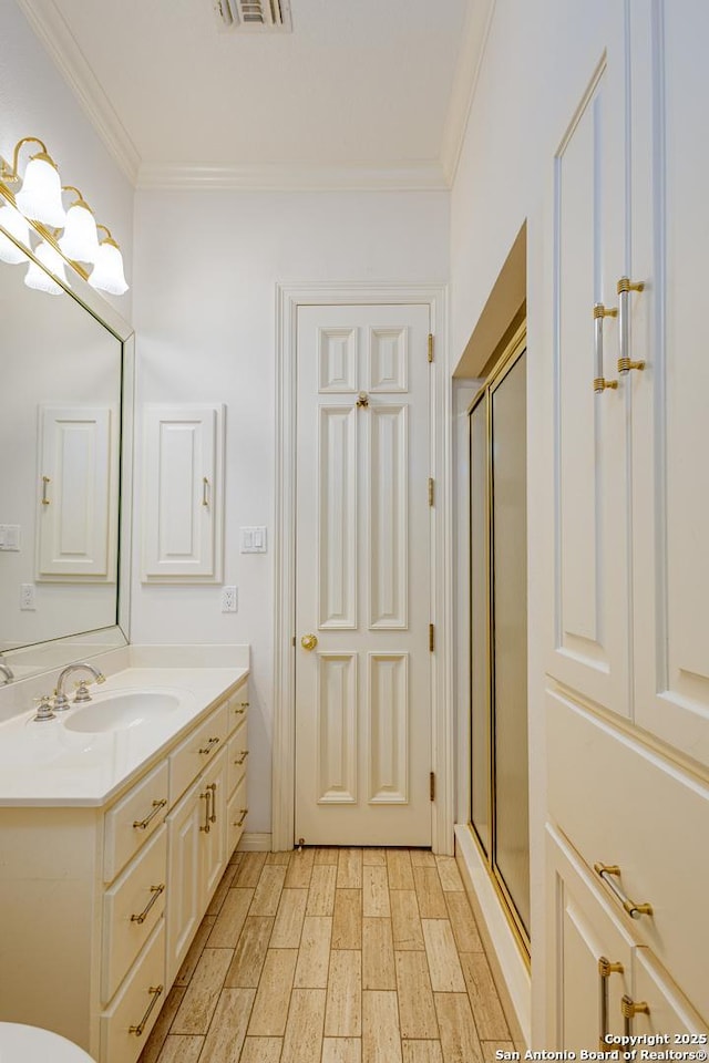 full bath featuring ornamental molding, a stall shower, wood finished floors, and vanity