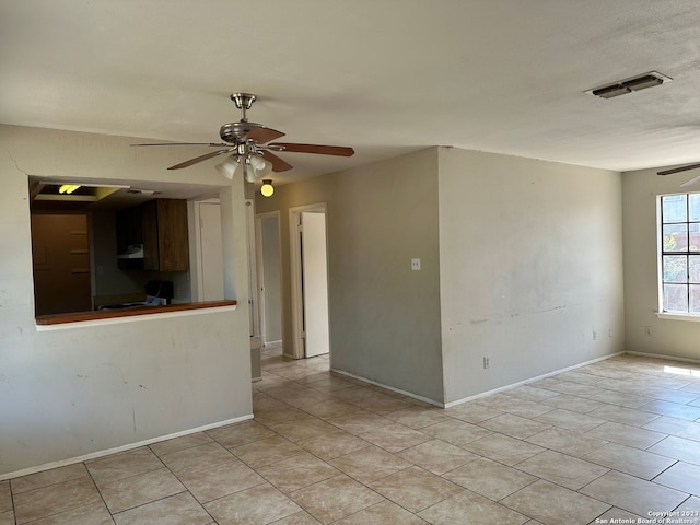 empty room with a ceiling fan, visible vents, baseboards, and light tile patterned floors