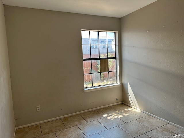 tiled spare room with baseboards and a wealth of natural light