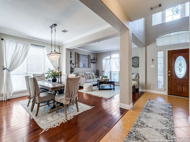 dining room with crown molding, baseboards, visible vents, and light wood-style floors