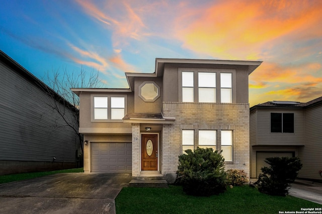 contemporary house featuring concrete driveway, brick siding, an attached garage, and stucco siding