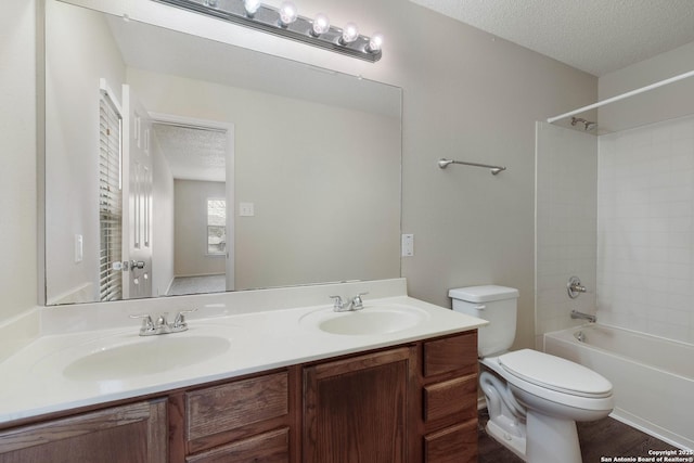 full bath featuring a textured ceiling, double vanity, a sink, and toilet