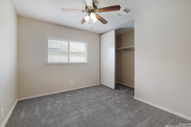 unfurnished bedroom featuring a textured ceiling, visible vents, a ceiling fan, a closet, and carpet