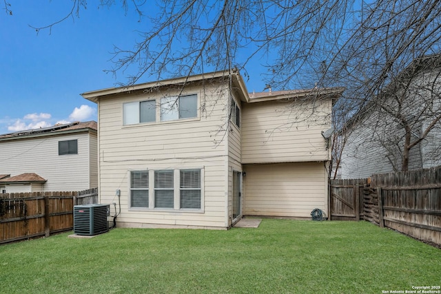 rear view of house featuring a fenced backyard, a yard, and central air condition unit