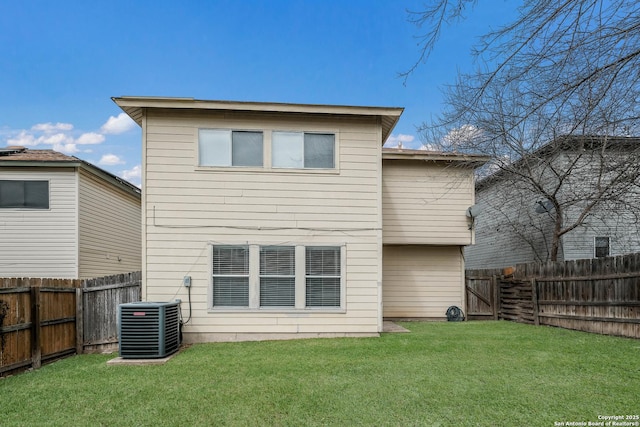 rear view of house with a fenced backyard, a yard, and central air condition unit