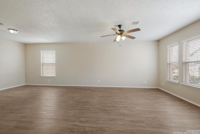 spare room with baseboards, visible vents, and wood finished floors