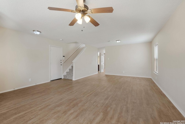 interior space with light wood-style flooring, baseboards, stairway, and a textured ceiling