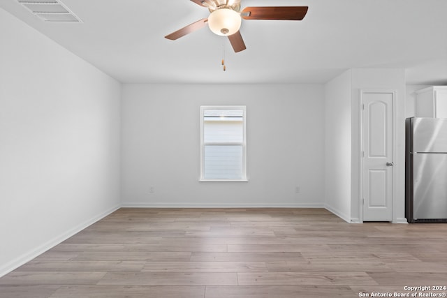 empty room with ceiling fan, light wood-type flooring, visible vents, and baseboards