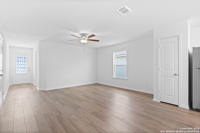 unfurnished living room with light wood-style floors, ceiling fan, visible vents, and baseboards