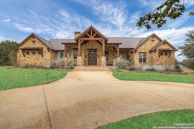 view of front of home featuring metal roof, concrete driveway, a standing seam roof, and stone siding