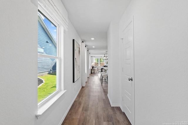 hallway with a chandelier, recessed lighting, wood finished floors, and baseboards