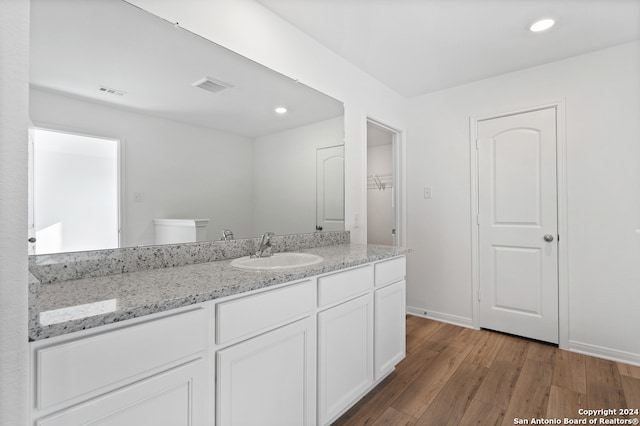 bathroom with visible vents, vanity, baseboards, and wood finished floors