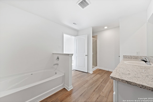 bathroom featuring visible vents, a stall shower, vanity, wood finished floors, and a bath