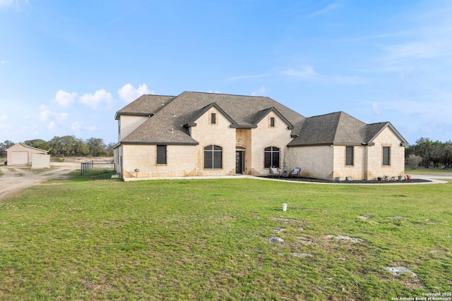 french country inspired facade featuring stone siding, roof with shingles, and a front lawn