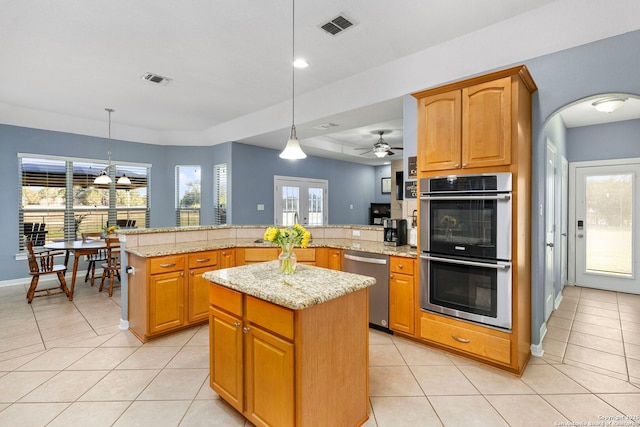 kitchen featuring a peninsula, light tile patterned floors, appliances with stainless steel finishes, and a center island