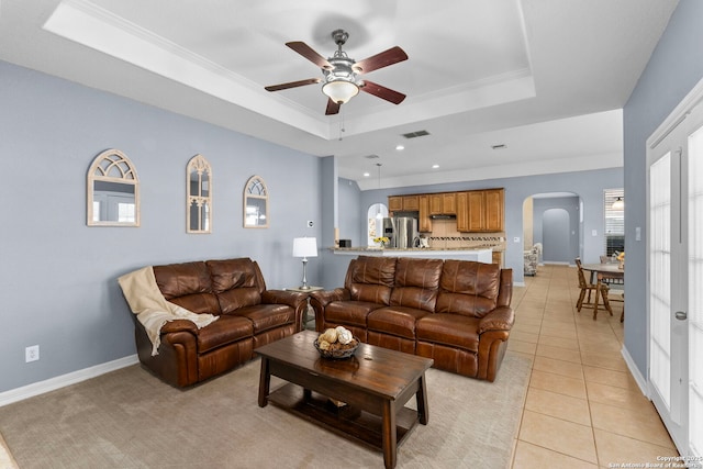 living area with visible vents, arched walkways, a tray ceiling, crown molding, and light tile patterned flooring