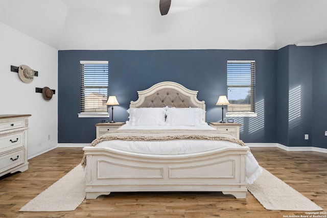 bedroom with ceiling fan, vaulted ceiling, baseboards, and wood finished floors