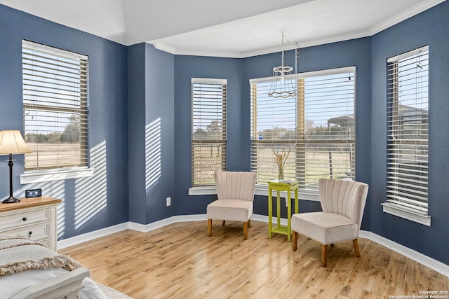 sitting room featuring baseboards, crown molding, wood finished floors, and a healthy amount of sunlight