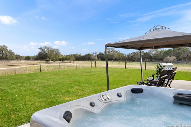 view of yard featuring a hot tub, a gazebo, fence, washer / dryer, and a rural view