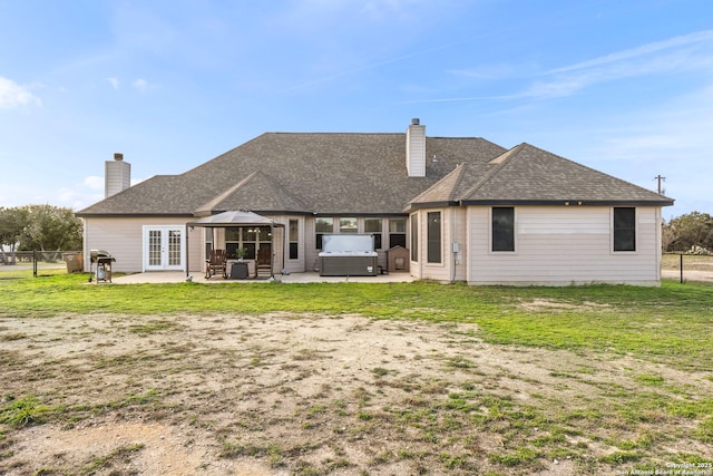 rear view of house featuring a hot tub, a patio, a chimney, fence, and french doors