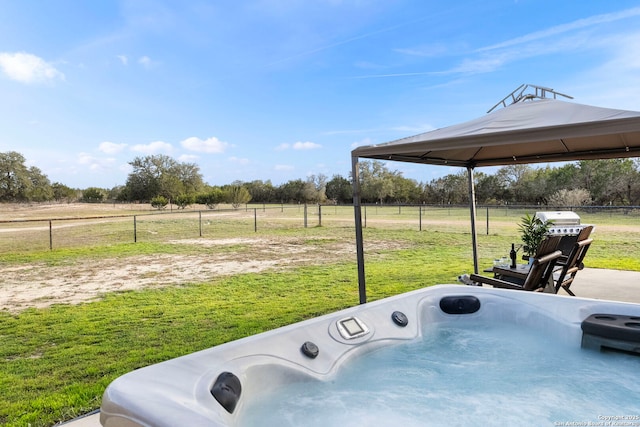 view of patio featuring a gazebo, a rural view, fence, and a hot tub