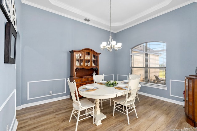 dining space with ornamental molding, visible vents, a notable chandelier, and wood finished floors