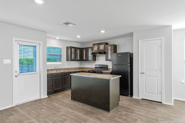 kitchen featuring light wood finished floors, visible vents, dark brown cabinetry, under cabinet range hood, and black appliances