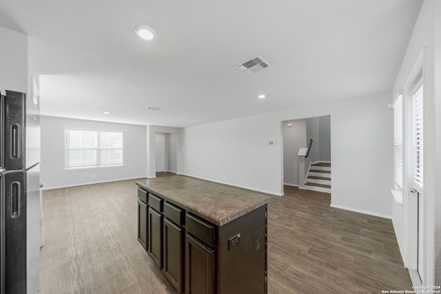 kitchen featuring visible vents, light wood-style floors, open floor plan, dark brown cabinets, and freestanding refrigerator