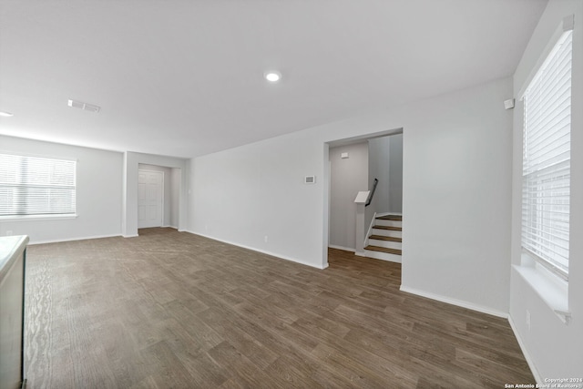 unfurnished living room with stairs, wood finished floors, visible vents, and baseboards