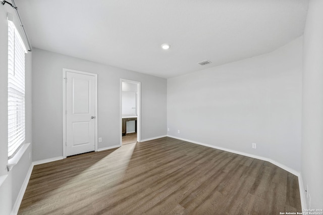 unfurnished room featuring wood finished floors, visible vents, and baseboards