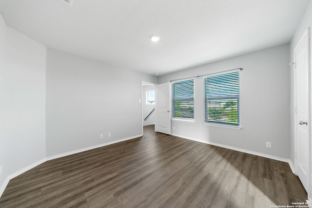 spare room with dark wood finished floors and baseboards