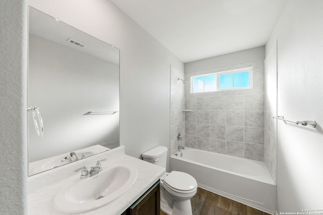 bathroom with toilet, shower / bath combination, wood finished floors, visible vents, and vanity