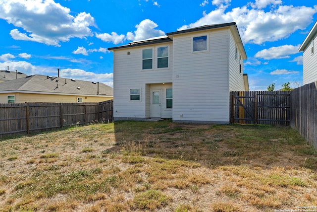 rear view of house with a fenced backyard and a yard