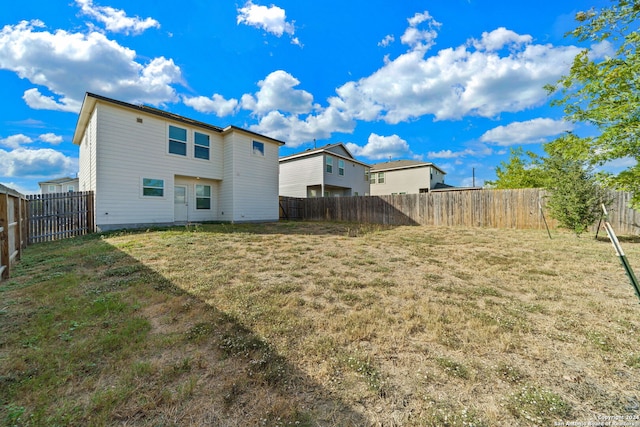 rear view of property with a lawn and a fenced backyard